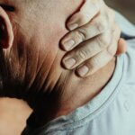 man with neck pian holding his neck