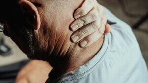 man with neck pian holding his neck